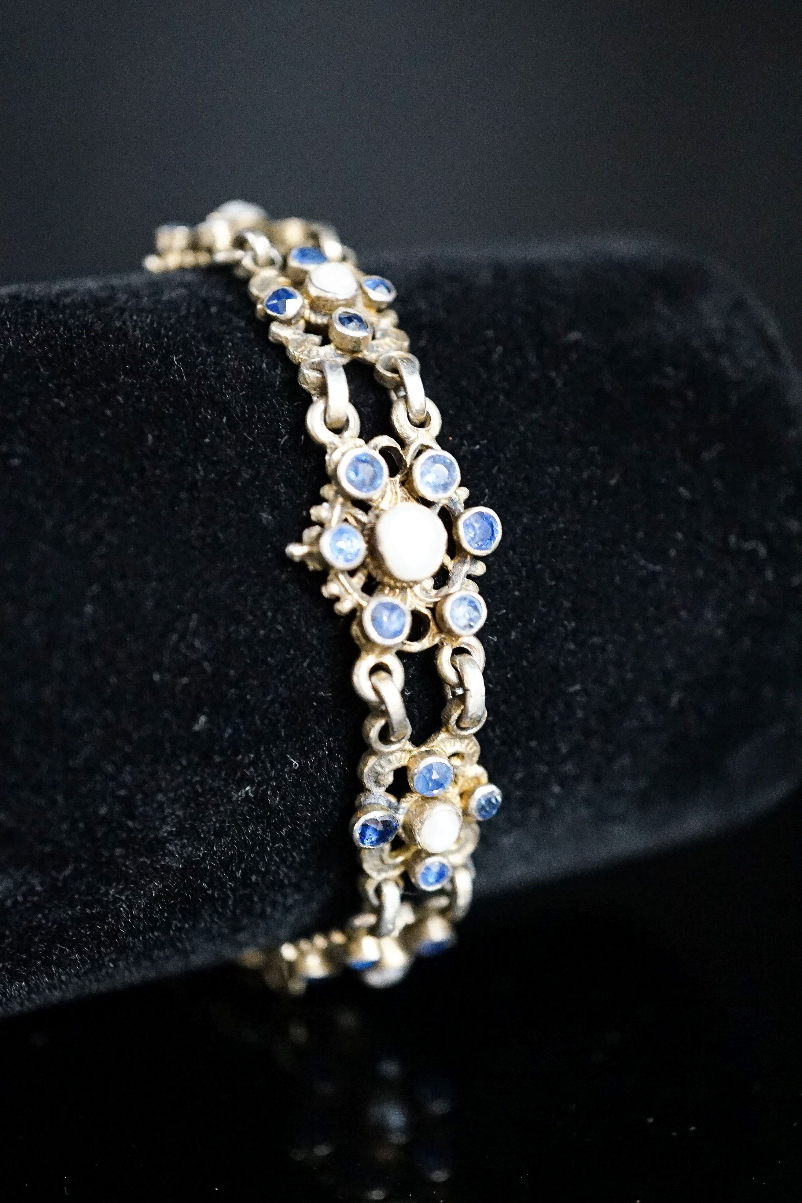 A continental gilt white metal, sapphire and split pearl flower head cluster set bracelet